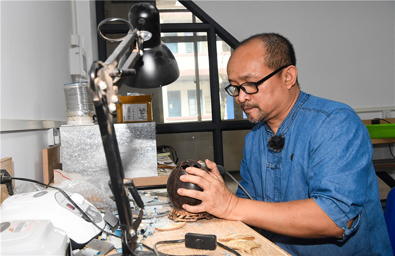 Zhang Bidi, artesano especializado en la talla en coco, trabaja en la ciudad de Qionghai, provincia de Hainan, 18 de febrero del 2022. [Foto: Xinhua]