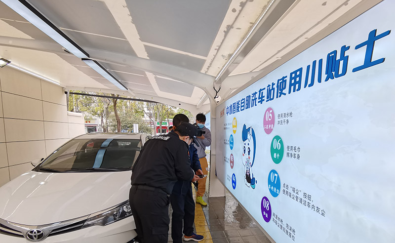 Un miembro del personal ayuda a un cliente a usar el servicio de autolavado de coches en una estación en Wuhan, el 23 de marzo de 2022. [Foto/IC]
