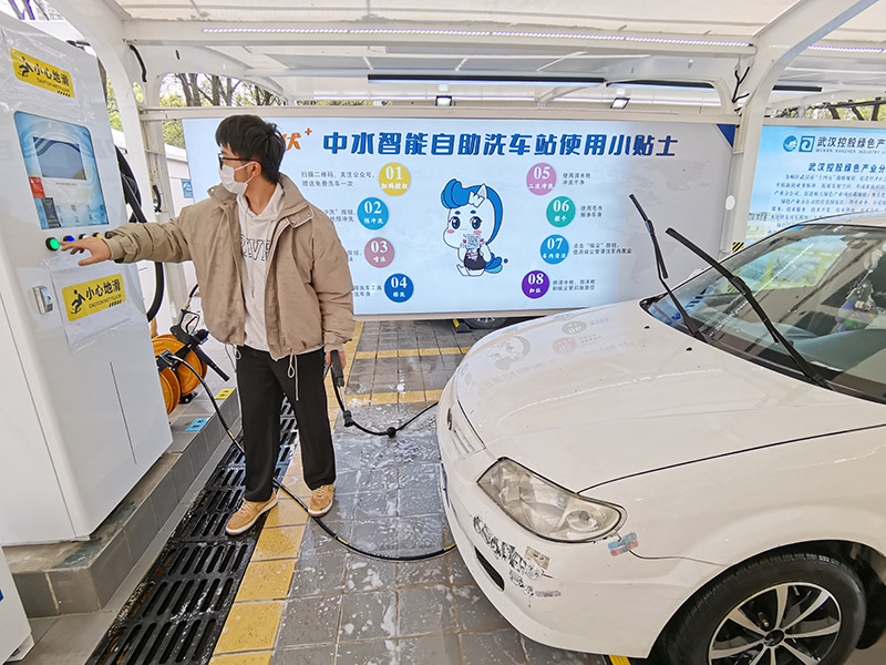 Un hombre prueba el servicio de lavado de coches de autoservicio en una estación en Wuhan, el 23 de marzo de 2022. [Foto/IC]