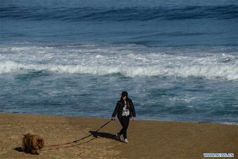 Una mujer pasea a su perro por la playa de Reñaca, en Viña del Mar, Chile, el 27 de junio de 2022. (Xinhua/Jorge Villegas) 