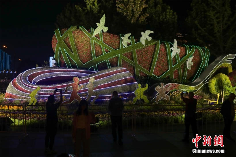 Se iluminan los adornos de flores con el tema del Día Nacional en Beijing