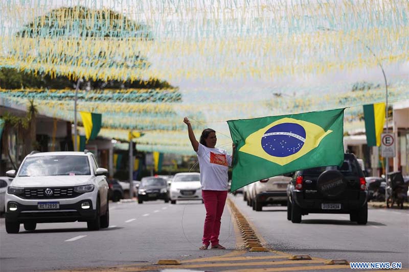 Una mujer cuelga una bandera nacional brasileña en una calle decorada con motivo de la participación de la selección nacional de fútbol de Brasil en la Copa Mundial de la FIFA Qatar 2022, en Brasilia, Brasil, el 16 de noviembre de 2022. (Xinhua/Lucio Tavora)