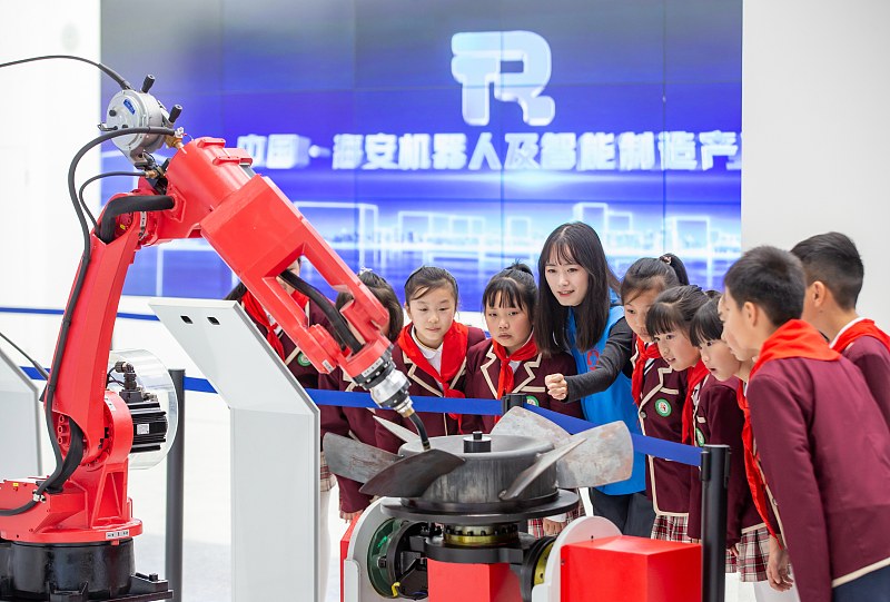 Los estudiantes de primaria y su maestra observan máquinas inteligentes artificiales en un centro de exposiciones en Nantong, provincia oriental china de Jiangsu, 10 de noviembre del 2022. [Foto: VCG]