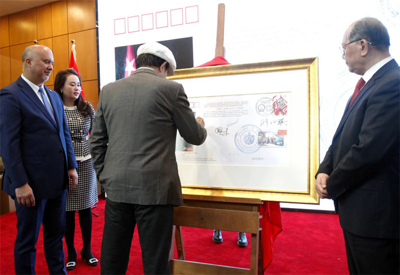 El escultor chino Yuan Xikun firma en el Museo Jintai de Beijing el sobre conmemorativo por la reciente visita a China del presidente cubano Miguel Díaz-Canel, 31 de enero del 2023. (Foto: YAC)