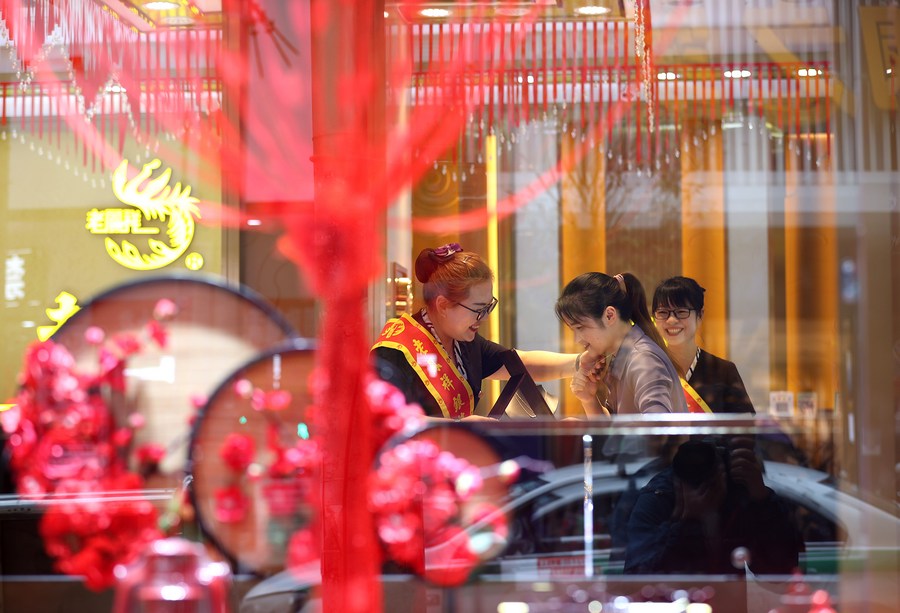 Una cliente prueba joyas de oro en una tienda durante las vacaciones del Festival del Medio Otoño en el distrito de Danzhai, en la provincia suroccidental china de Guizhou, el 11 de septiembre de 2022. (Huang Xiaohai/Xinhua)