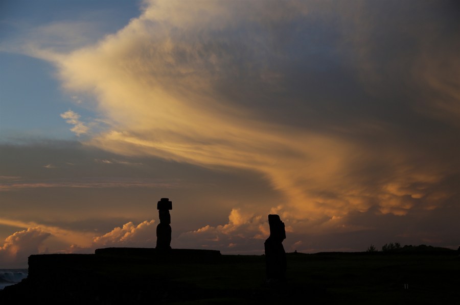 Imagen del 7 de julio de 2018 de la vista de la puesta del sol detrás las estatuas moai, en el sitio arqueológico de Ahu Tahai, cerca de Hanga Roa, capital de la Isla de Pascua, Chile. (Xinhua/Wang Pei)