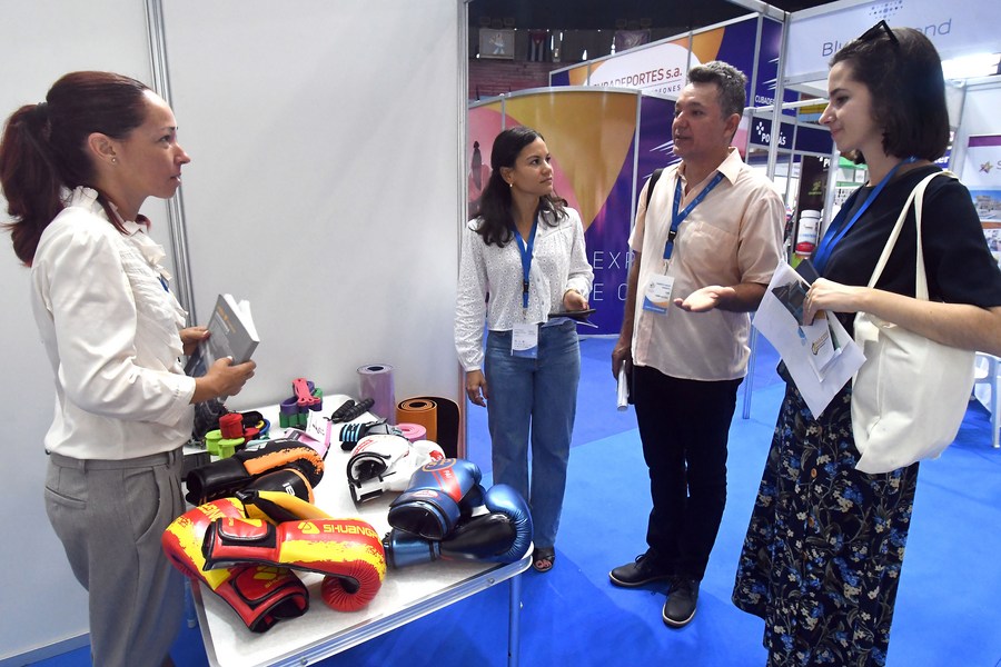 Imagen del 1 de agosto de 2023 de una trabajadora conversando con visitantes en el estand de la empresa china Yiwu Kinghan Export and Import durante la I Feria Internacional del Deporte en el Coliseo de la Ciudad Deportiva, en La Habana, capital de Cuba. (Xinhua/Joaquín Hernández)