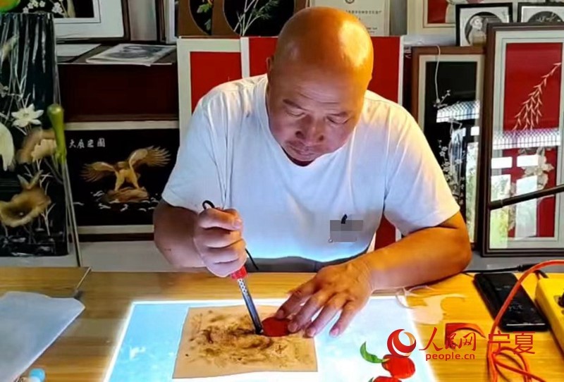 Weng Guosheng, un artesano de 54 años de la región autónoma Hui de Ningxia, en el noroeste de China, utiliza un soldador para planchar y colorear pajitas de trigo mientras crea una pintura con este material especial. (Diario del Pueblo digital/Li Tiantian)