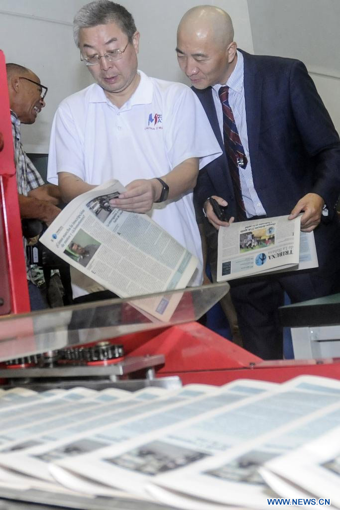 Imagen del 19 de agosto de 2023 del embajador chino en Cuba, Ma Hui (i), observando un periódico en su visita al proyecto de reconversión tecnológica para la producción de la prensa y otros materiales gráficos en Cuba, en La Habana, capital de Cuba. Cuba moderniza hoy la industria poligráfica, con un crédito otorgado a través del Banco de Exportación e Importación de China, que ha permitido mejorar el equipamiento y acelerar los procesos de impresión y distribución en la isla caribeña. (Xinhua/Str) 