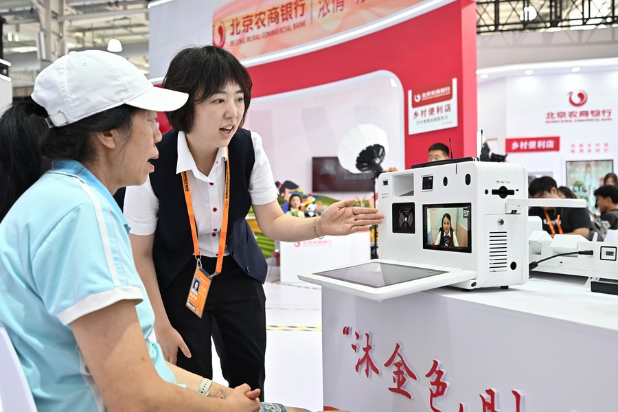 Una empleada del Banco Comercial Rural de Beijing presenta un dispositivo de banco por video a una visitante durante la Feria Internacional de Comercio de Servicios de China 2023 (CIFTIS, siglas en inglés) en el Parque Shougang de Beijing, la capital de China, el 3 de septiembre de 2023. (Xinhua/Li Xin)