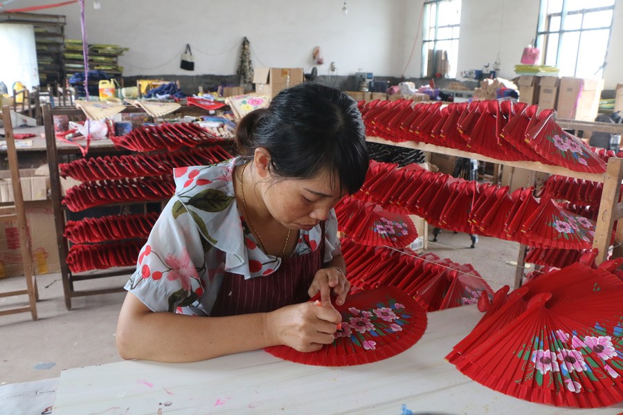 Yu Xiuying pinta un abanico de madera artesanal en el taller de la empresa Jiangxi Shenglian Fan Development Company Limited del poblado Ganzhu del distrito Guangchang, en la provincia de Jiangxi, en el este de China, el 12 de septiembre de 2023. (Xinhua/Zhu Yunuo)