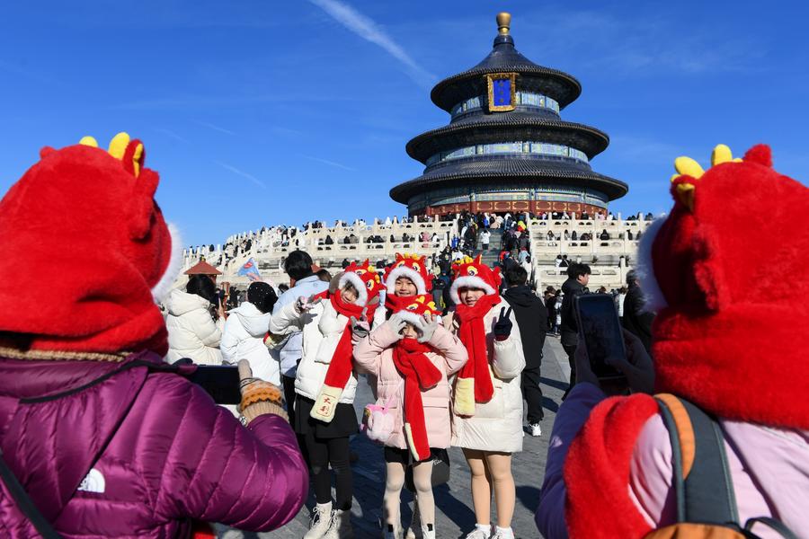 Turistas de Malasia posan para fotografías con sombreros con temática de dragones en el Templo del Cielo, en Beijing, la capital de China, el 23 de enero de 2024. (Xinhua/Ju Huanzong)