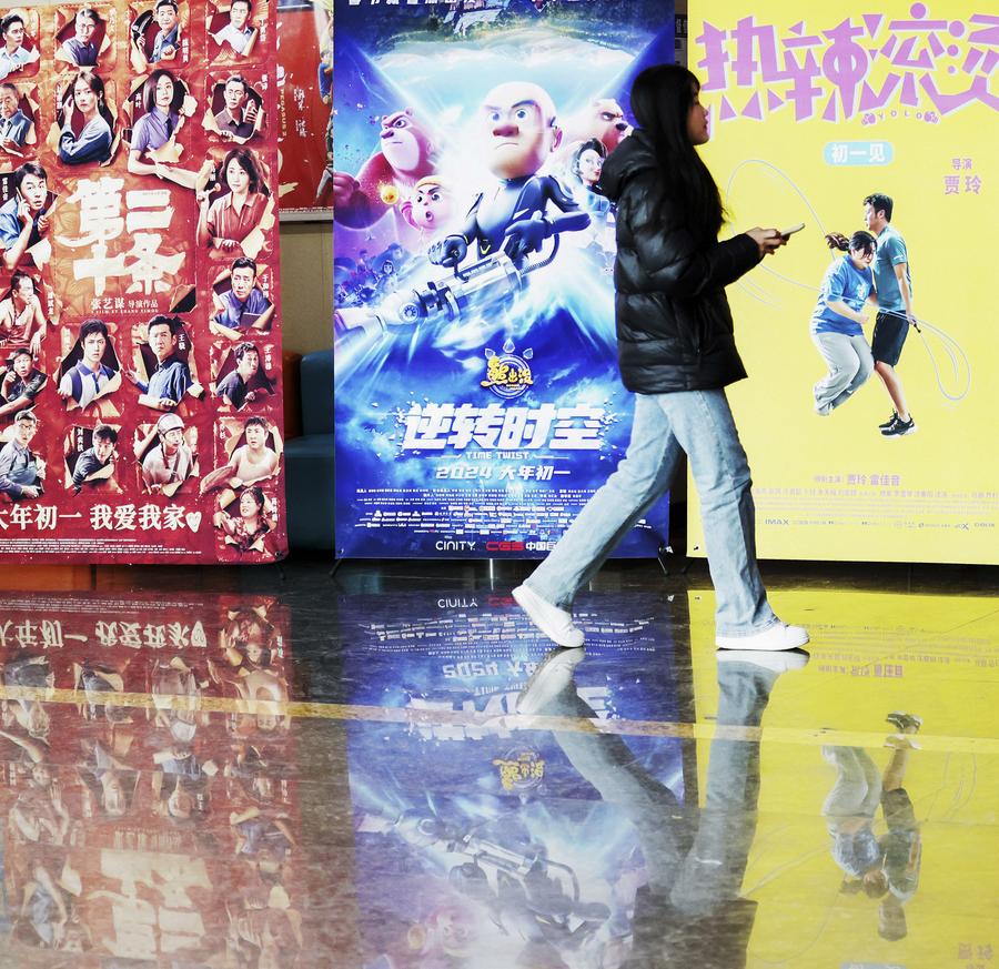 Una joven camina junto a carteles de películas en un cine en el distrito de Tancheng de la ciudad de Linyi, en la provincia de Shandong, en el este de China, el 15 de febrero de 2024. (Xinhua/Zhang Chunlei)