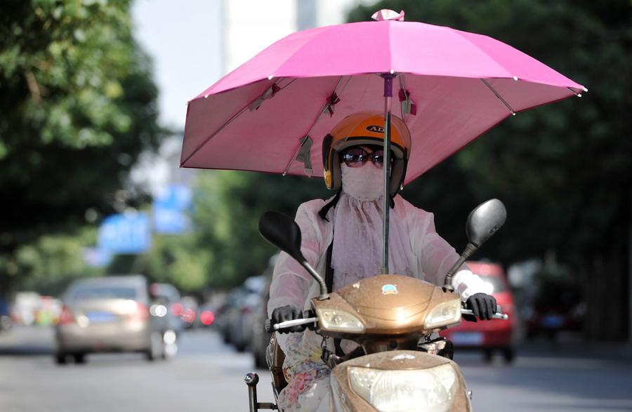 En esta foto de archivo, una mujer conduce una bicicleta eléctrica mientras se protege con una sombrilla en Yinchuan, capital de la región autónoma de la etnia hui de Ningxia, en el noroeste de China. (Xinhua/Peng Zhaozhi)