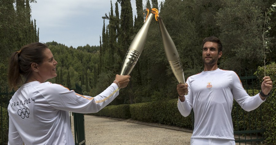 El primer portador de la antorcha, el campeón olímpico griego de remo, Stefanos Ntouskos (d), enciende la antorcha de la segunda portadora de la antorcha, la campeona olímpica francesa de natación, Laure Manaudou, durante el relevo de la antorcha después de la ceremonia de encendido de la llama olímpica de los Juegos Olímpicos de París 2024, en la Antigua Olimpia, Grecia, el 16 de abril de 2024. (Xinhua/Marios Lolos)