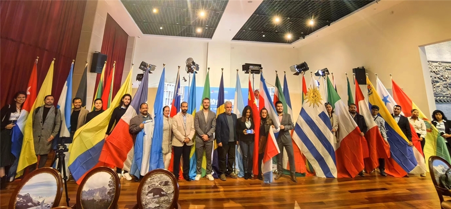 Periodistas de los países latinoamericanos tomaron fotos junto con las banderas nacionales colgadas en el Centro de Intercambio Cultural China-América Latina de Beijing (Foto/Wei Longyu)