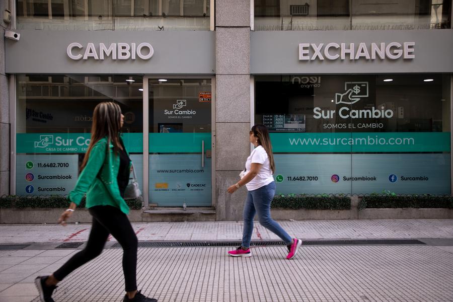 Personas caminan frente a un local de venta de divisas en el Microcentro, zona financiera de la ciudad de Buenos Aires, capital de Argentina, el 6 de marzo de 2024. (Xinhua/Martín Zabala) 