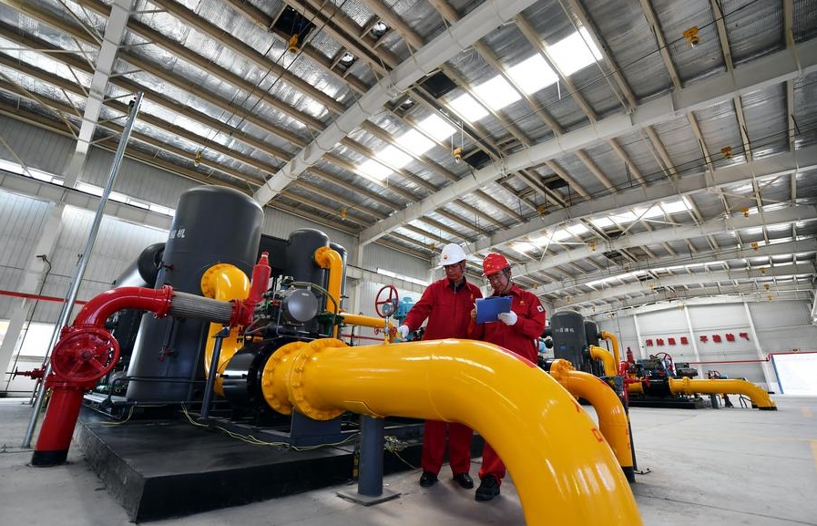 En esta foto, tomada el 25 de junio de 2022, dos trabajadores revisan equipos en el taller de una base minera de metano de capas carboníferas en el distrito de Qinshui, en la provincia septentrional china de Shanxi. (Xinhua/Wang Feihang)