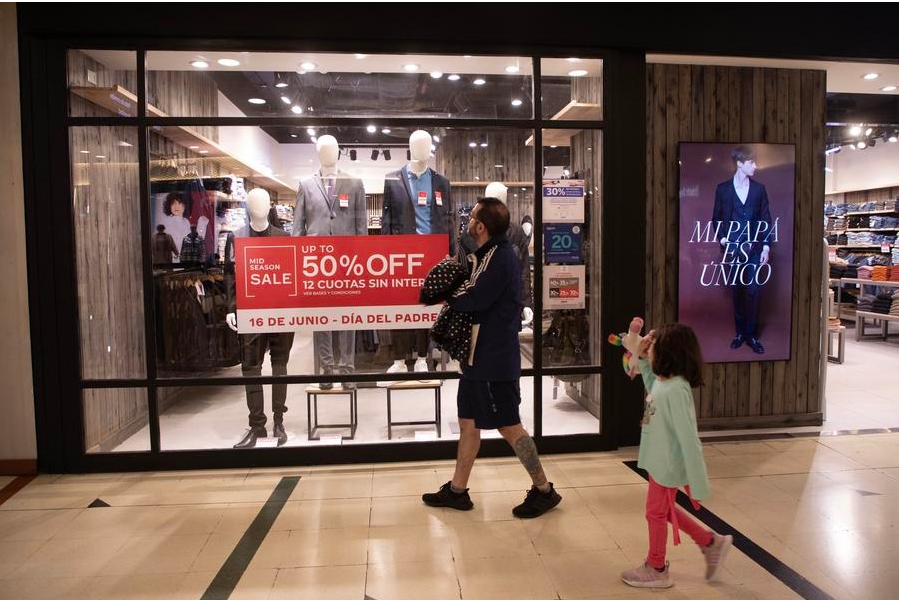 Imagen del 14 de junio de 2024 de un hombre observando un escaparate de un local de venta de ropa masculina junto a su hija, en Buenos Aires, capital de Argentina. (Xinhua/Martín Zabala) 