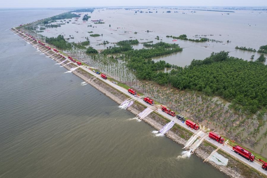 La foto aérea, tomada con un dron, muestra a rescatistas drenando el agua anegada en un dique del lago Dongting, en el poblado de Tuanzhou, distrito de Huarong, subordinado a la ciudad de Yueyang, en la provincia central china de Hunan, el 9 de julio de 2024.  (Xinhua/Chen Sihan)