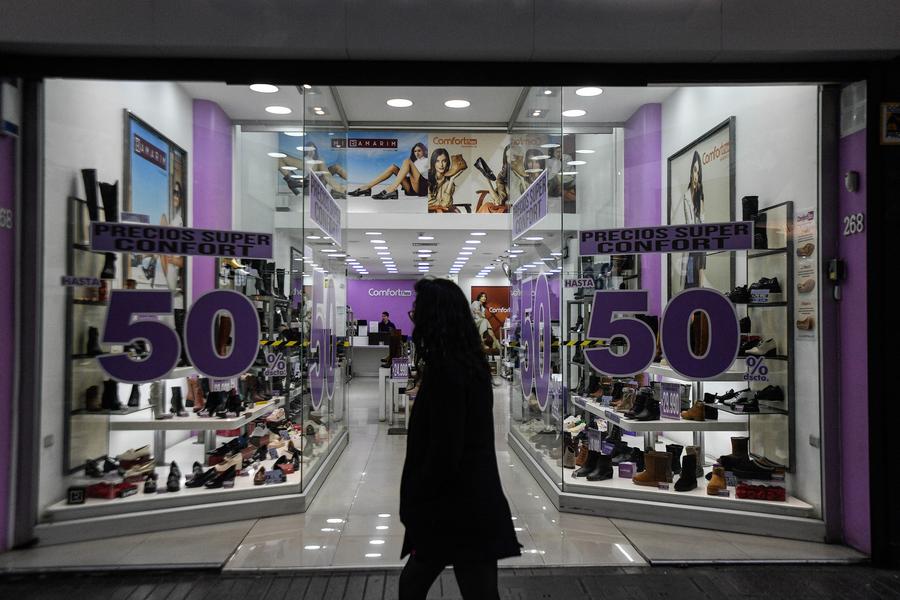 Una mujer camina frente a una tienda de zapatos, en Santiago, capital de Chile, el 1 de julio de 2024. (Xinhua/Jorge Villegas) 