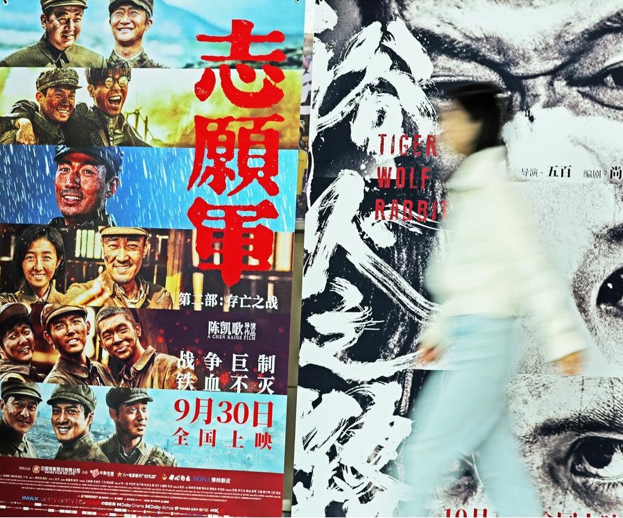 Una mujer camina junto a carteles de películas en un cine en el distrito de Tancheng, en la provincia oriental china de Shandong, el 7 de octubre de 2024. (Xinhua/Zhang Chunlei)