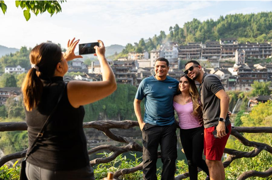 Visitantes extranjeros se toman fotos en el sitio escénico del poblado de Furong, distrito de Yongshun, prefectura autónoma de las etnias tujia y miao de Xiangxi, provincia de Hunan, en el centro de China, el 7 de noviembre de 2024. (Xinhua/Chen Sihan)