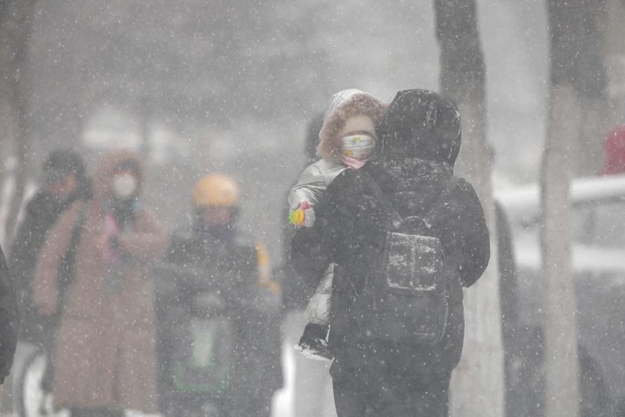 Un peatón carga a un niño en un día nevado en Qiqihar, en la provincia nororiental china de Heilongjiang, el 25 de noviembre de 2024. (Xinhua/Wang Yonggang)