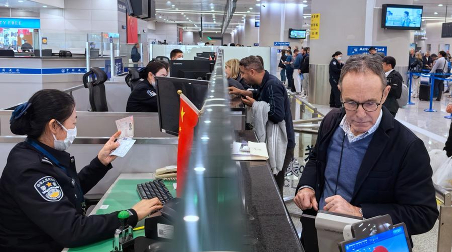 Agentes de la policía fronteriza revisan documentos de viajeros en un puesto de control fronterizo del Aeropuerto Internacional Pudong de Shanghai, metrópoli del este de China, el 14 de marzo de 2024. (Xinhua/Wei Wenheng)