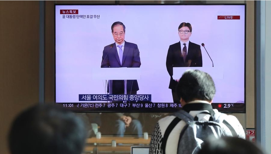 Personas observan una transmisión televisiva en vivo del líder del partido gobernante de la República de Corea, Han Dong-hoon (d), y el primer ministro, Han Duck-soo, reuniéndose con la prensa, en una estación de tren en Seúl, la capital del país, el 8 de diciembre de 2024. (Xinhua/Yao Qilin)