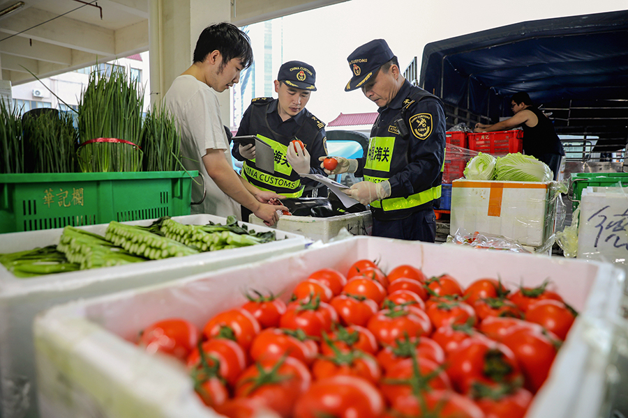 Funcionarios de aduanas inspeccionan los productos comercializados entre la parte continental de China y Macao. [Foto: Yu Bo/ China Daily]