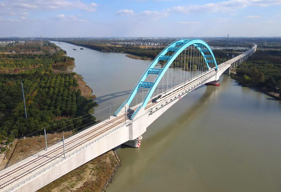 Esta foto aérea tomada el 23 de noviembre de 2024 muestra un tren bala cruzando el puente Qingpu, que hace parte de una nueva línea ferroviaria de alta velocidad que conecta la municipalidad de Shanghai con las provincias de Jiangsu y Zhejiang, todas en el este de China. (Xinhua/Fang Zhe)