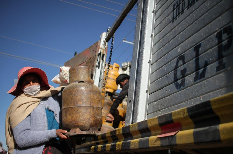 Una mujer porta una mascarilla mientras sostiene un tanque de gas reabastecido de un camión cerca de una planta de gas licuado de petróleo en Senkata, El Alto, Bolivia, el 28 de julio de 2020. (XinhuaMateo Romay)