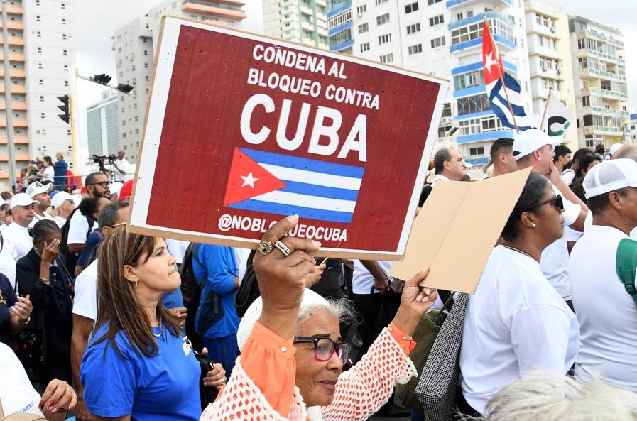 Imagen del 20 de diciembre de 2024 de una mujer sosteniendo un cartel durante una marcha para exigir el fin del bloqueo que aplica Washington contra Cuba, en La Habana, capital de Cuba. (Xinhua/Joaquín Hernández) 