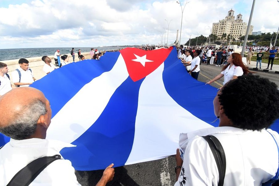 Imagen del 20 de diciembre de 2024 de personas sosteniendo una bandera nacional cubana durante una marcha para exigir el fin del bloqueo que aplica Washington contra Cuba, en La Habana, capital de Cuba. (Xinhua/Joaquín Hernández) 