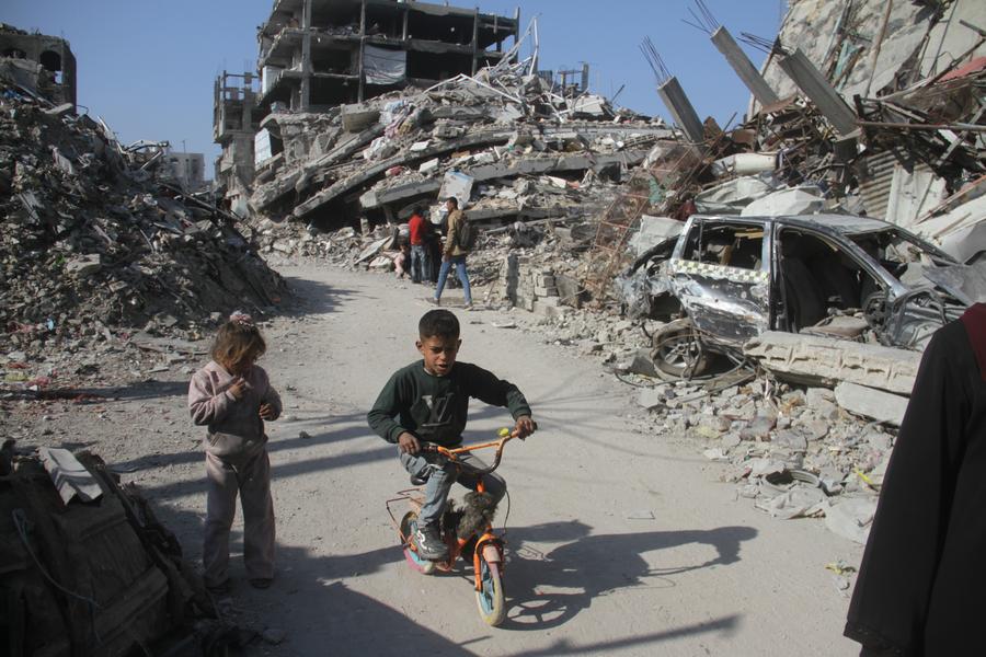 Imagen del 29 de enero de 2025 de niños palestinos vistos en una calle con edificios destruidos en el campamento de refugiados de Jabalia, en el norte de la Franja de Gaza. (Xinhua/Abdul Rahman Salama) 