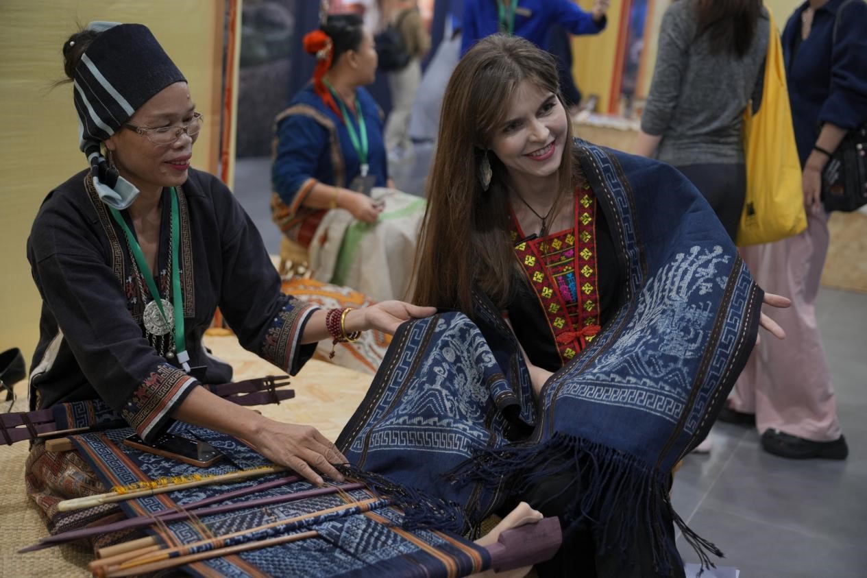 Una mujer rusa se maravilla con las técnicas textiles tradicionales de Li en la Semana Cultural Mundial del Brocado y el Bordado de Hainan 2024 (4.ª) celebrada en la provincia de Hainan, en el sur de China, el 8 de noviembre de 2024. (Foto de Zhang Mao/Diario del Pueblo digital)