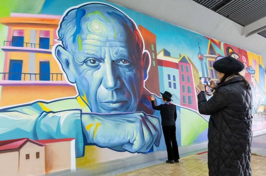 Pasajeros toman fotos a un retrato de Pablo Picasso que hace parte de un mural en la estación de metro Longyang Road, en Shanghai, este de China, el 7 de diciembre de 2023. (Xinhua/Wang Xiang)