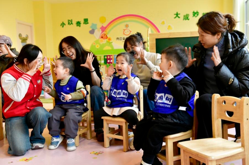 Maestras y madres juegan con un grupo de niños en un jardín infantil en la ciudad de Rizhao, en la provincia oriental china de Shandong, el 20 de febrero de 2025. (Xinhua/Guo Xulei)