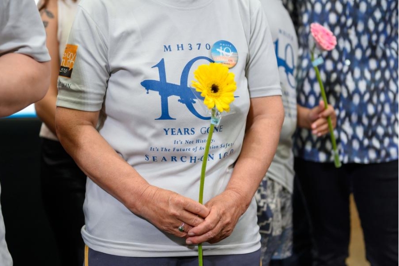 Varias personas sostienen flores durante un acto para conmemorar el décimo aniversario de la desaparición del vuelo MH370, en Subang Jaya, estado de Selangor, Malasia, el 3 de marzo de 2024. (Xinhua/Chong Voon Chung)