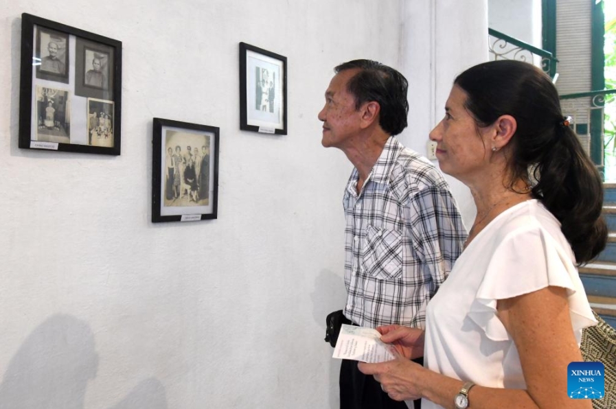  Personas observan fotografías durante la exposición "Raíces en el Caribe. Familias sino-cubanas: tradición y fusión", en la Casa de las Artes y Tradiciones Chinas, en el Barrio Chino de La Habana, capital de Cuba, el 11 de junio de 2025. El Barrio Chino de La Habana recordó con la apertura de una exposición fotográfica la llegada a Cuba hace 178 años de los primeros culíes, quienes dejaron una profunda huella en la historia y en la formación de la nacionalidad cubana. (Xinhua/Joaquín Hernández)