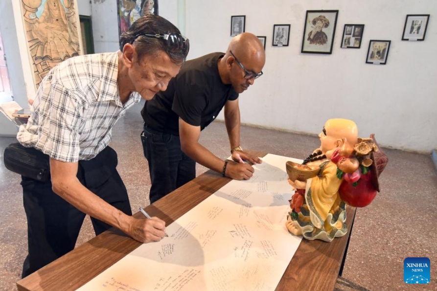 Personas escriben sus impresiones sobre la exposición "Raíces en el Caribe. Familias sino-cubanas: tradición y fusión" en la Casa de las Artes y Tradiciones Chinas, en el Barrio Chino de La Habana, capital de Cuba, el 11 de junio de 2025. El Barrio Chino de La Habana recordó con la apertura de una exposición fotográfica la llegada a Cuba hace 178 años de los primeros culíes, quienes dejaron una profunda huella en la historia y en la formación de la nacionalidad cubana. (Xinhua/Joaquín Hernández)