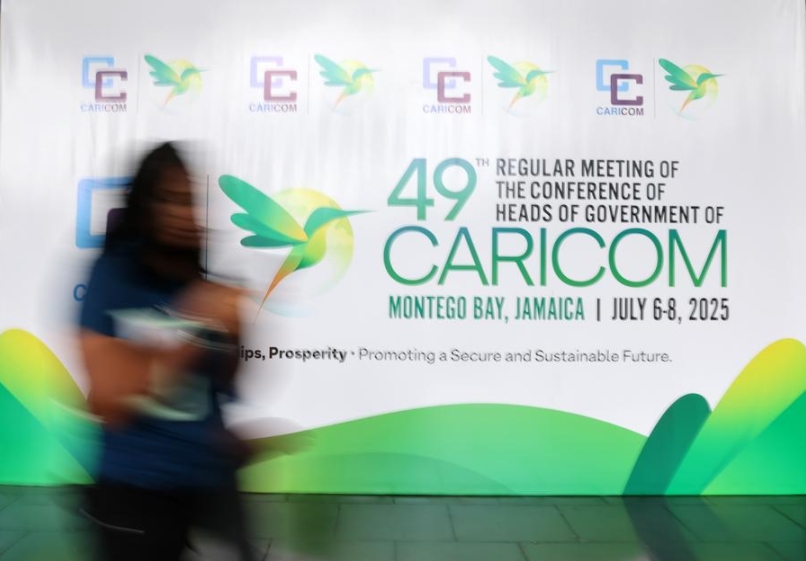 Imagen del 6 de julio de 2025 de una mujer pasando junto a una valla publicitaria of la 49ª Reunión Ordinaria de la Conferencia de Jefes de Gobierno de la Comunidad del Caribe (CARICOM) en Montego Bay, Jamaica (Xinhua/Li Mengxin)