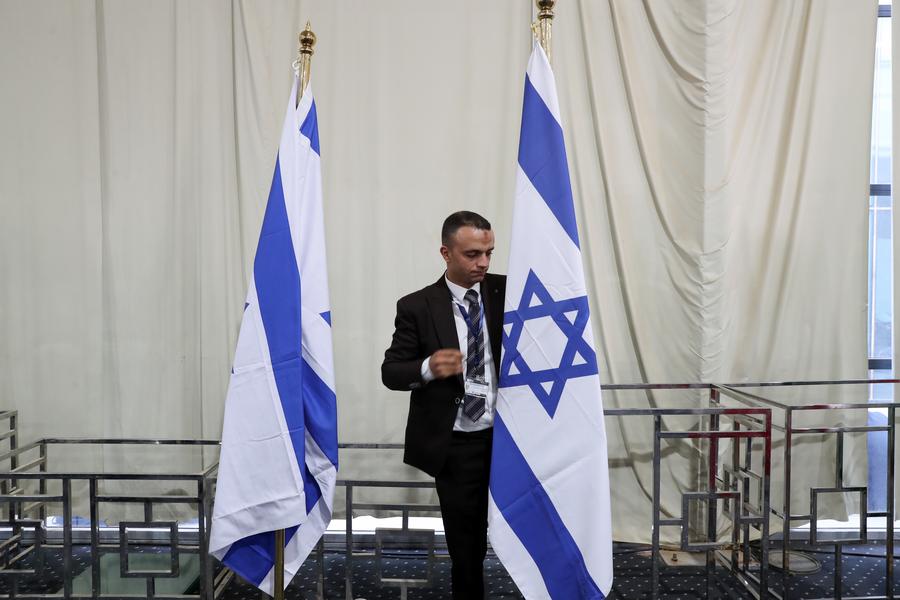 Un empleado arregla la bandera nacional israelí, en el centro de medios de la sede de la cumbre para consolidar el alto el fuego entre Israel y Hamás, en Sharm el-Sheikh, Egipto, el 13 de octubre de 2025. (Xinhua/Sui Xiankai) 
