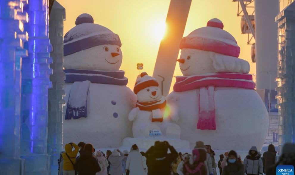 Turistas se divierten en el atardecer en el Mundo de Hielo y Nieve de Harbin