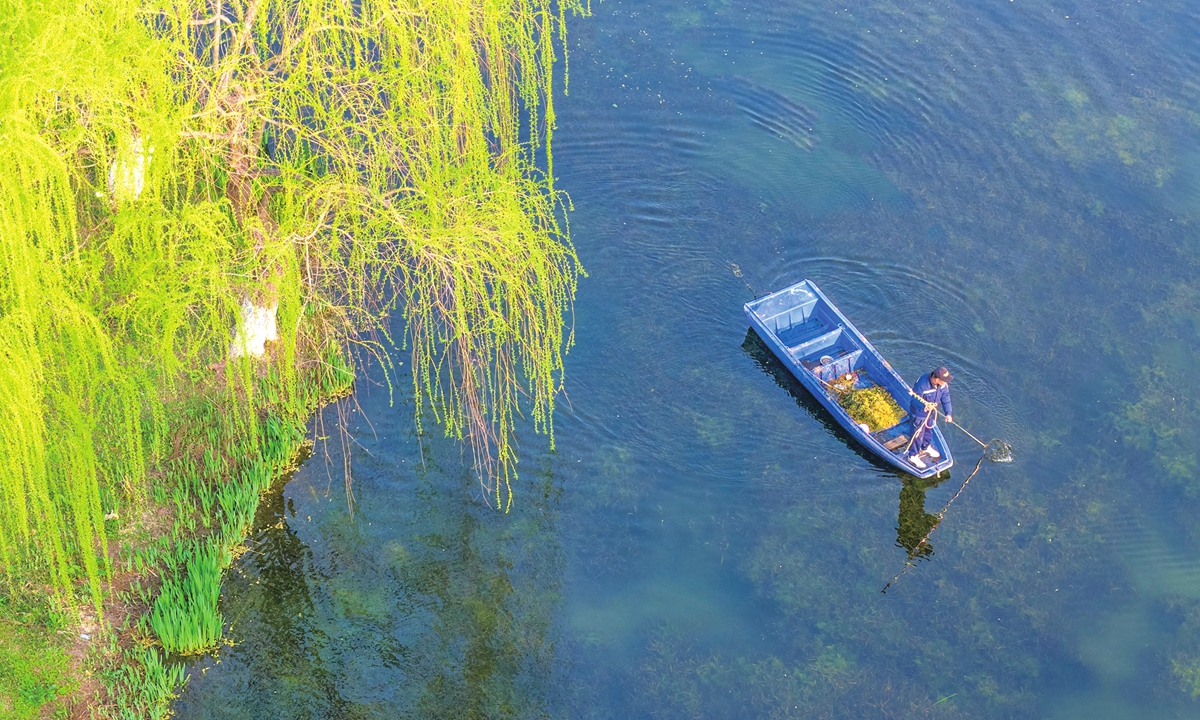Miembro del personal limpia escombros flotantes en el Lago Xuanwu en Nanjing, en la provincia de Jiangsu, como parte de los esfuerzos del Día Mundial del Agua para preservar el entorno, 22 de marzo de 2026. (Foto: VCG)