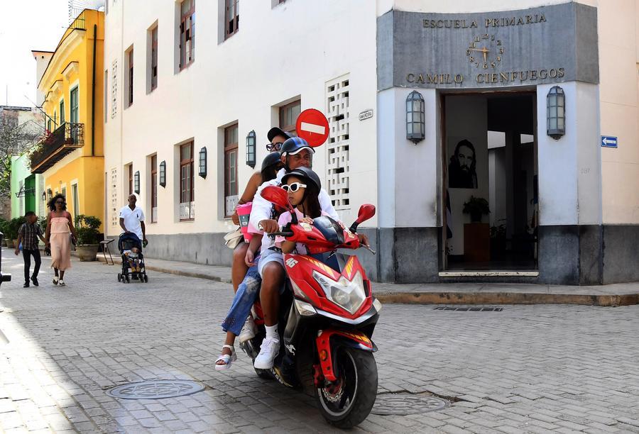 Personas circulan en una motocicleta eléctrica frente a una escuela primaria, en La Habana, capital de Cuba, el 11 de abril de 2026. (Xinhua/Joaquín Hernández)