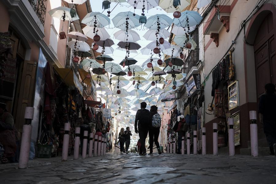 Imagen de archivo de personas caminando por una calle peatonal decorada con sombrillas de colores, en La Paz, Bolivia, el 24 de agosto de 2022. (Xinhua/Mateo Romay)