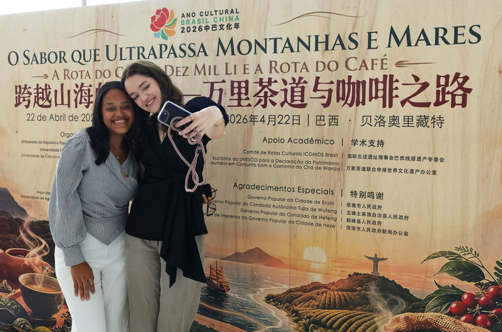Personas se hacen "selfies" durante el acto inaugural de la exposición itinerante "Sabores que cruzan océanos y montañas: la ruta del té y la ruta del café", celebrado en la Universidad Federal de Minas Gerais, en la ciudad brasileña de Belo Horizonte, el 22 de abril de 2026. (Xinhua/Jin Haoyuan)