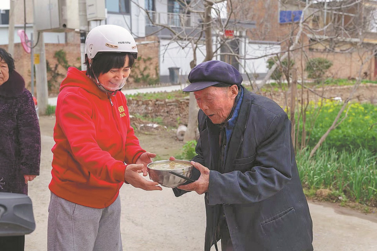Yue Aping entrega un tazón de fideos a un anciano en Xinzhuang, NuevaÁrea de Xixian, provincia de Shaanxi. (Foto: Zhao Hua/ China Daily)